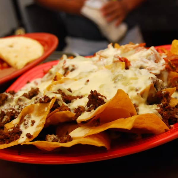 A red plate of Patron Mexican Grill nachos with melted cheese and ground beef.
